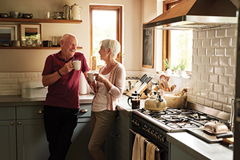 A couple drinking coffee in their kitchen. Links to Gifts of Real Estate